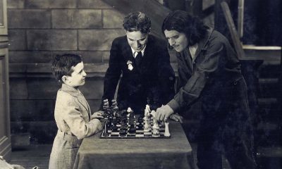 Reshevsky jogando xadrez com Douglas Fairbanks enquanto Charlie Chaplin os observa durante as filmagens do filme mudo americano Os Três Mosqueteiros em 1921.
