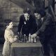 Reshevsky jogando xadrez com Douglas Fairbanks enquanto Charlie Chaplin os observa durante as filmagens do filme mudo americano Os Três Mosqueteiros em 1921.