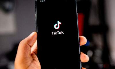 Mão segurando um celular com a logo do TikTok no meio da tela